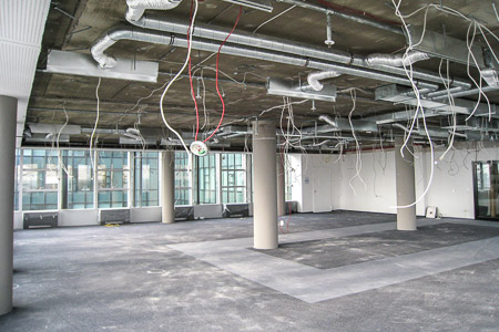 Auf der Baustelle: Kabel hängen von der Decke, Lüftungsrohre sind sichtbar.